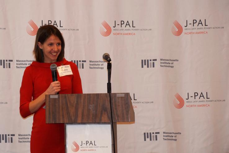 Mary Ann Bates speaking behind a podium with MIT and J-PAL logos in the background