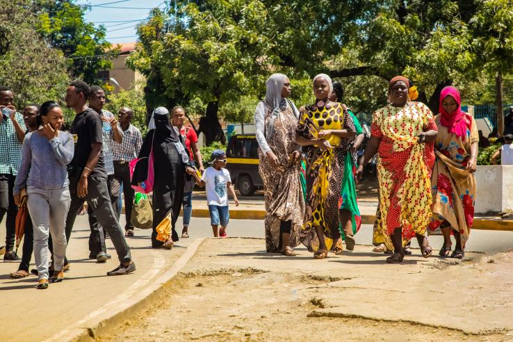 Women in Kenya walk along town street while in conversation. 
