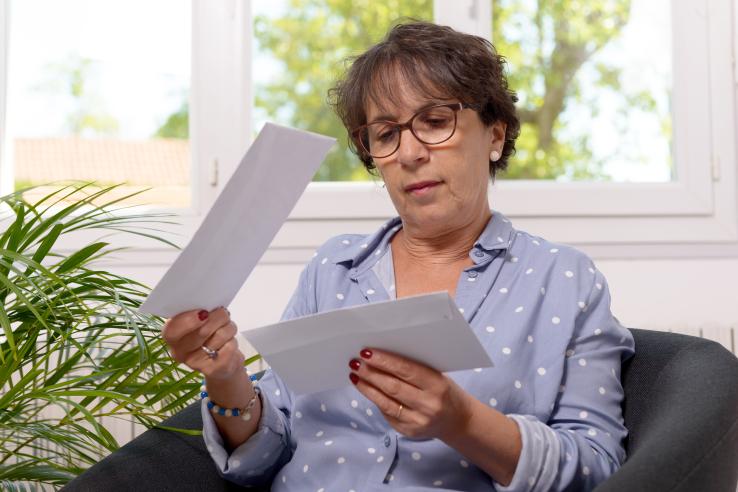 A woman opens her mail while sitting in a chair