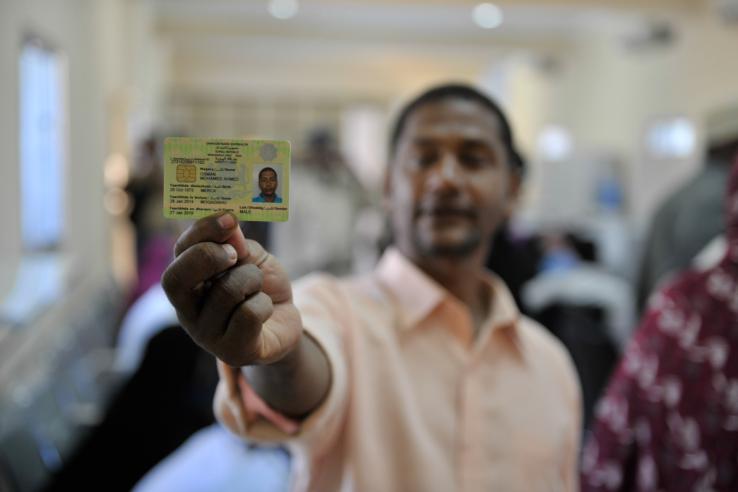 A man holds up his physical ID card.
