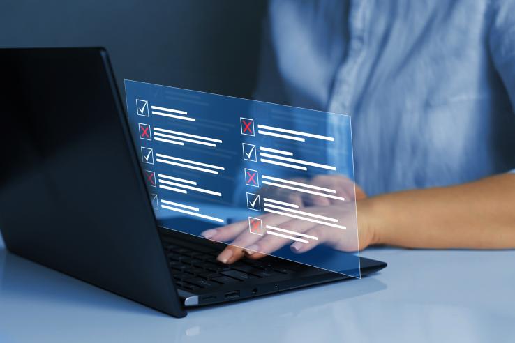 A person types on a laptop with a checklist graphic.
