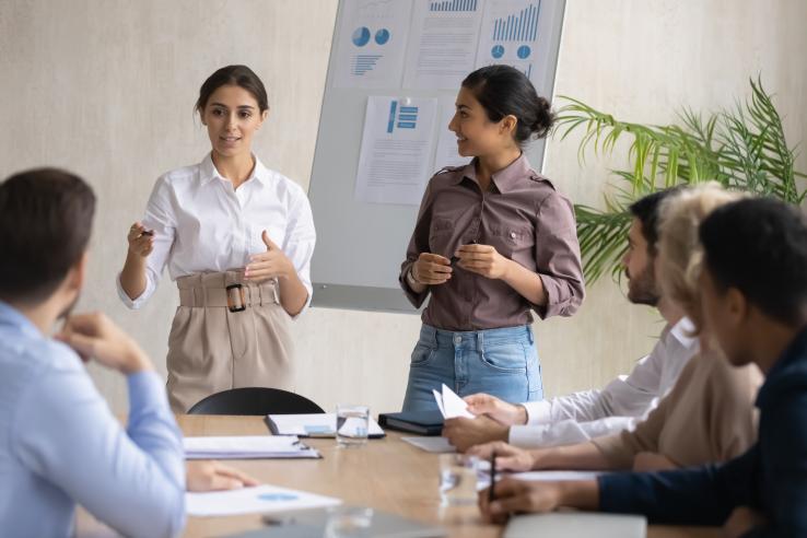 Two individuals presenting a poster to a table of others