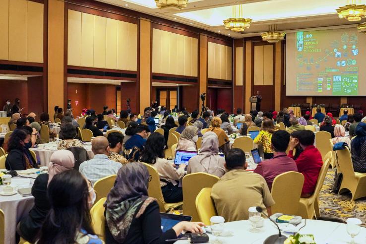 Conference participants sit at round tables watching a presenter on stage at J-PAL SEA's Emerging Challenges in the Environment Landscape: Addressing Climate Change, Sustainability, and Poverty conference.