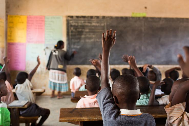 Children raising their hands in a classroom.