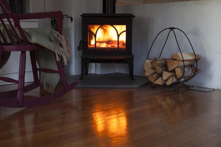 The photo shows a small woodburning fireplace inside a cozy home.