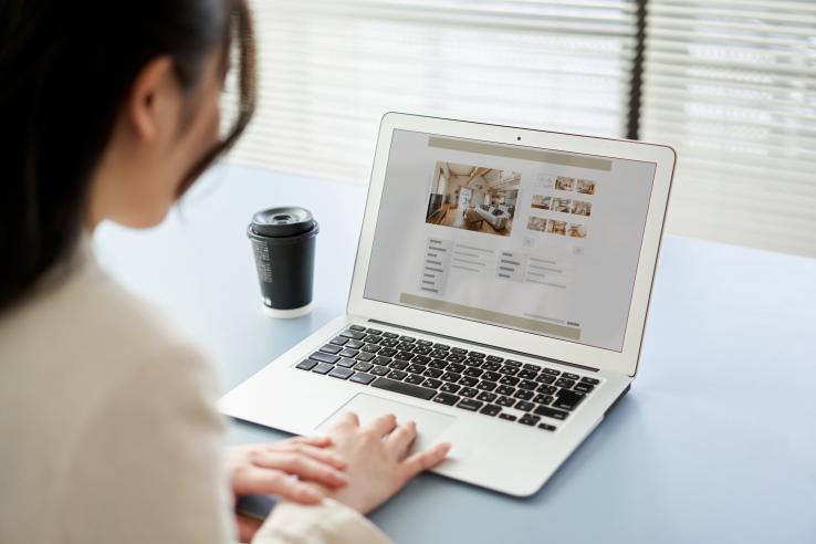 A person looks at housing listings on a laptop