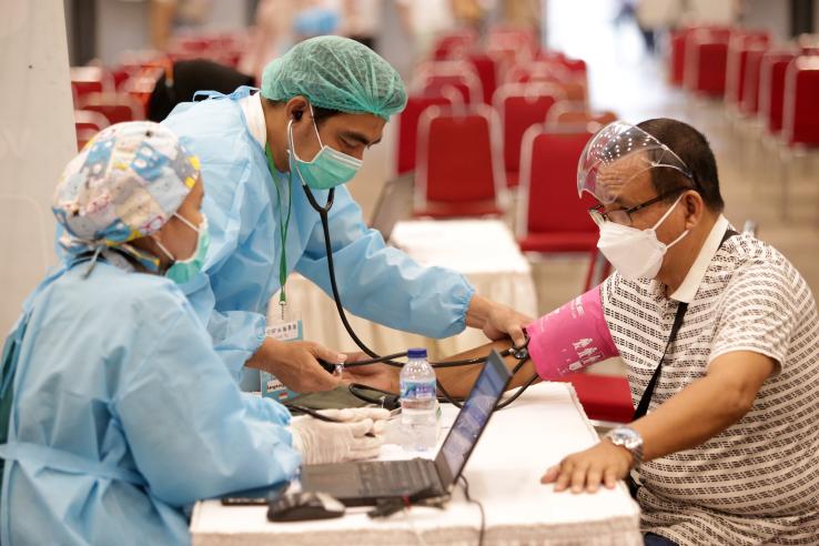 Elderly people are having their temperature and blood pressure checked before being receiving a Covid vaccine