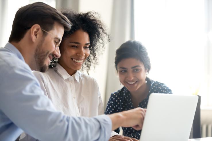 Three people smiling looking at computer screen together