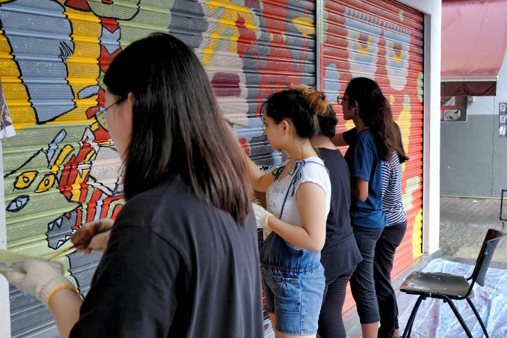 Three young adults paint a mural 