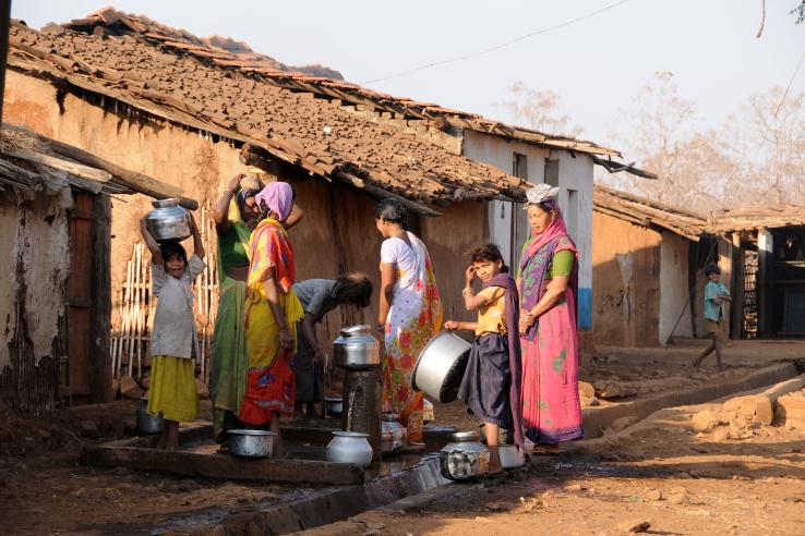 Indian women carry water on their heads in pots from well.