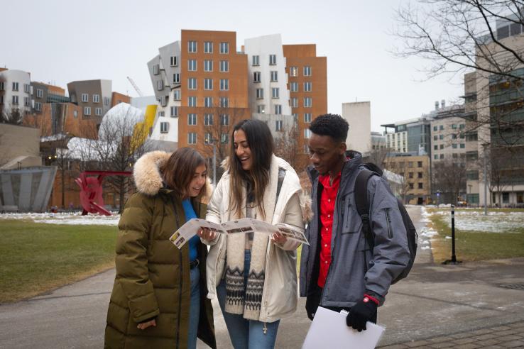 Photo of three DEDP master's students reviewing an informational pamphlet