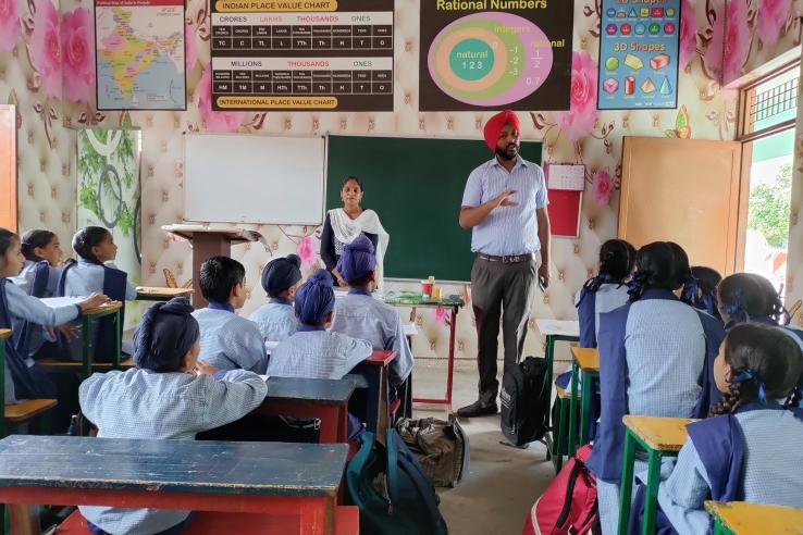 a man and women teaching children in a classroom in india