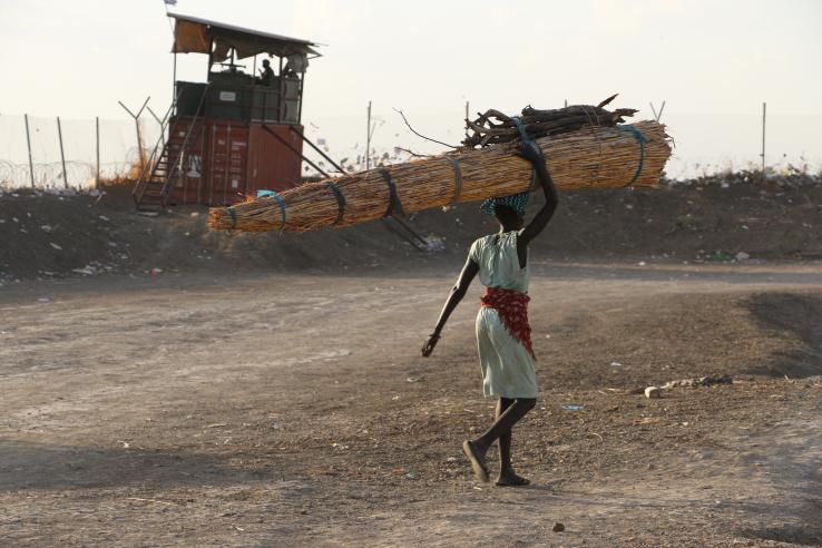 HPI woman walking in a refugee camp carrying items on her head