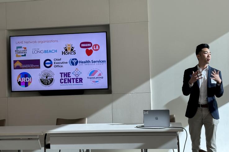 Vincent standing next to a presentation screen showing LAHE Network organizations