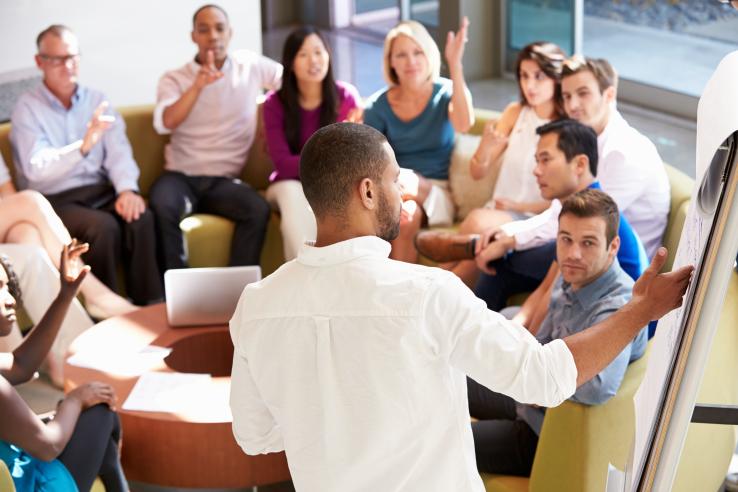 A man presenting in front of a seated group of people