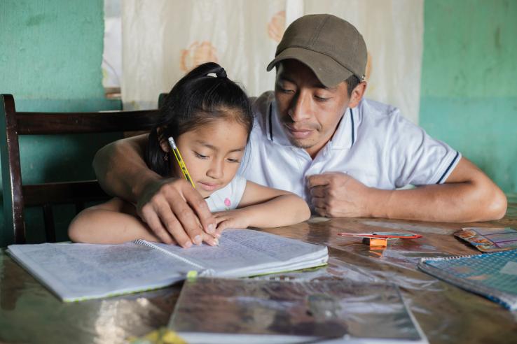 man supports his daughter on her homework