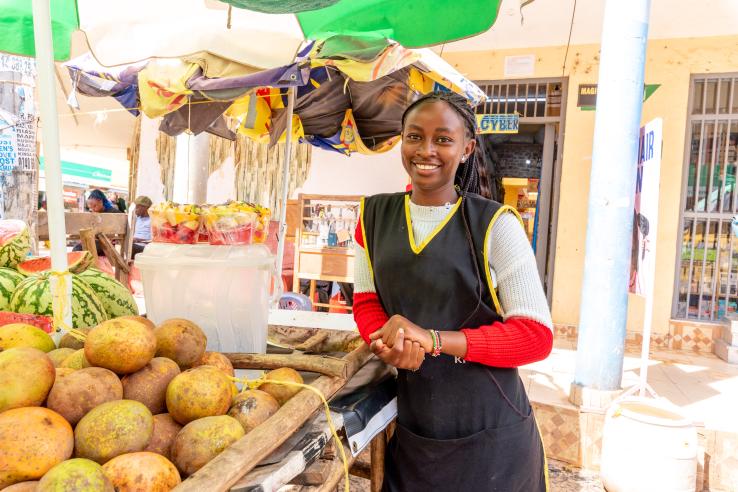 A woman stands in front of her fruit stand