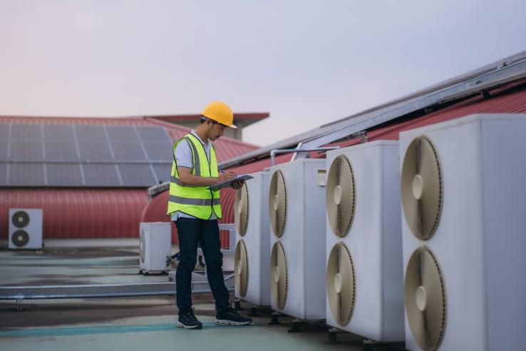 An engineer inspecting HVAC on a roof.
