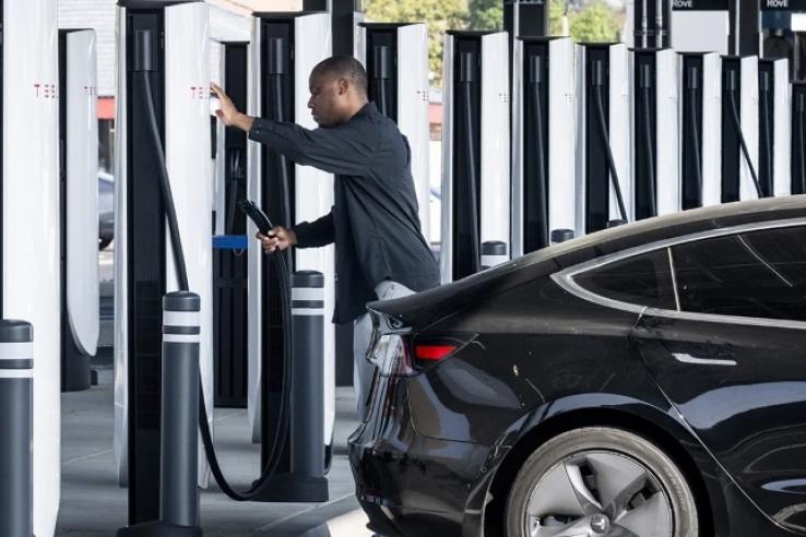 Man charging electric vehicle at mass charging station