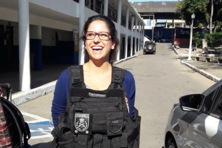 A woman stands on a road wearing a police vest.