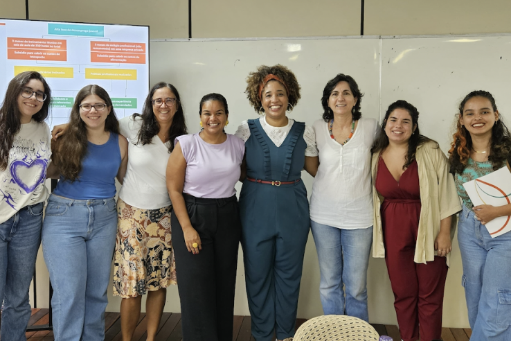 A group of women stand arm in arm in a classroom.