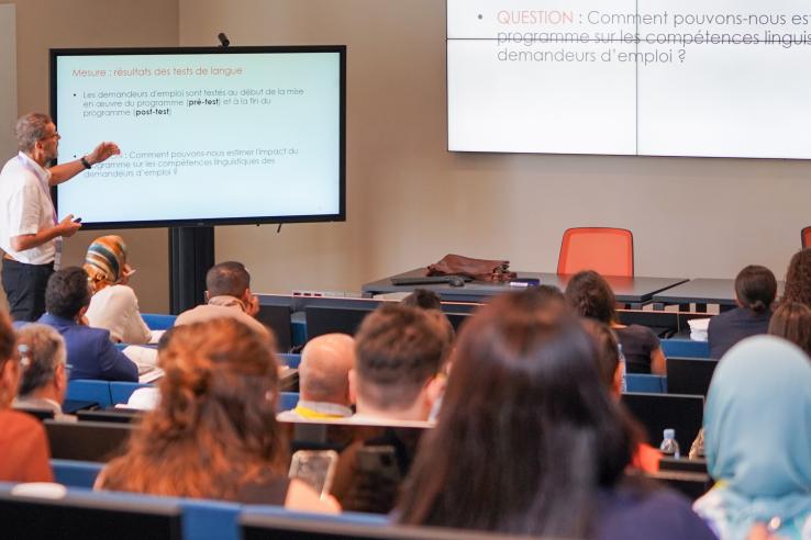 Speaker pointing to slide in front of large classroom