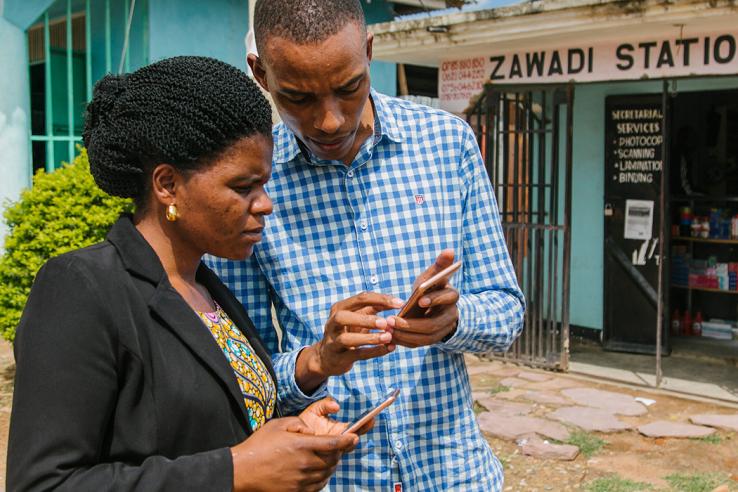 Man and woman standing in front of a store looking at their phones