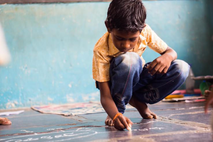 A child drawing in chalk on the floor