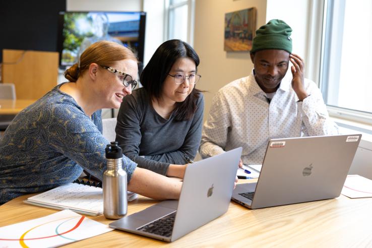 Three people look at computers