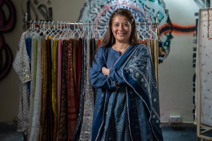 Women entrepreneur standing in front of garments smiling