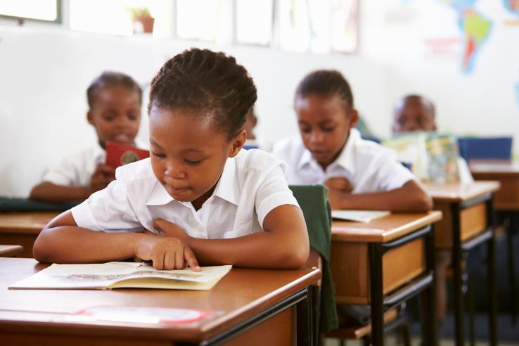 Young students in a classroom reading while sitting at desk