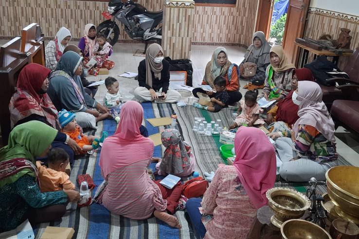 A group of women sit in a circle playing with their young babies