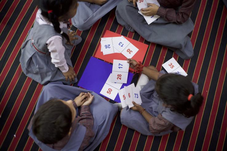 Four children sit in a circle playing the number comparison game