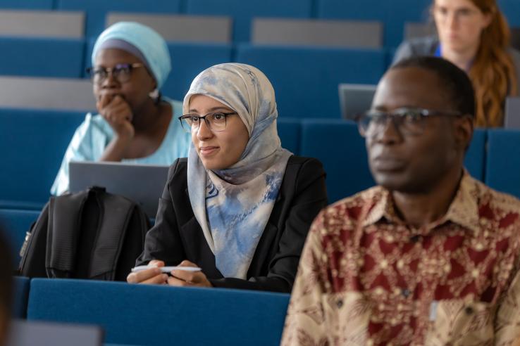 Female student smiles while sitting in a classroom next to other students