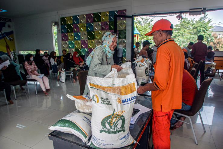 Woman smiles as we collects rice from a busy community hall