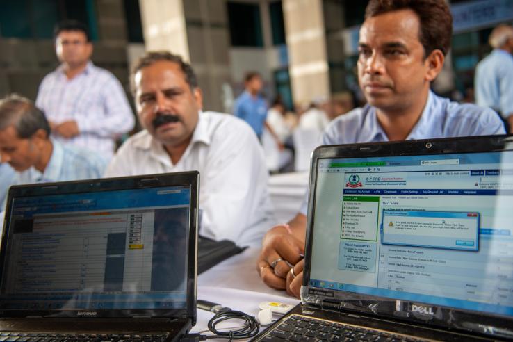 Two men sit behind computer screens that display e-filing information