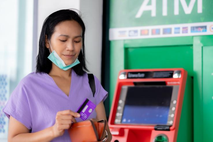 Woman holding a debit card while standing outside a bank