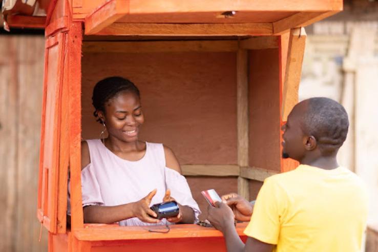 man giving his credit card to a woman in a pos service kiosk