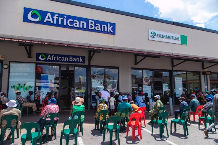 People waiting outside bank for government grant payment.