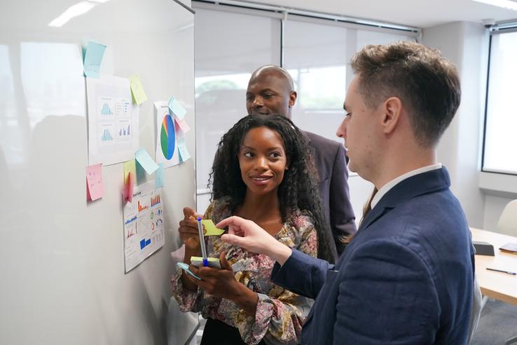 young entrepreneur of small company putting a adhesive note on glass in office during team meeting formulating business strategies.