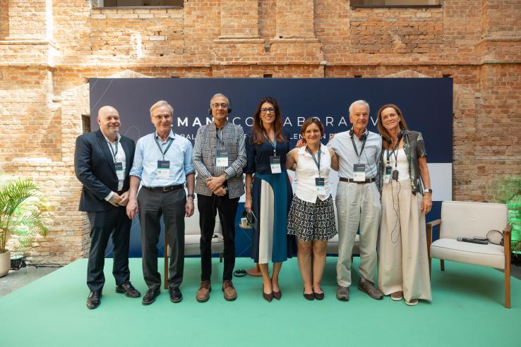 Group of people posing for photo during event on stage, with dark background