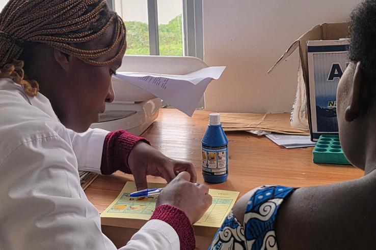 A nurse introducing the program to a beneficiary during a vaccination visit at Kinigi Health Centre.