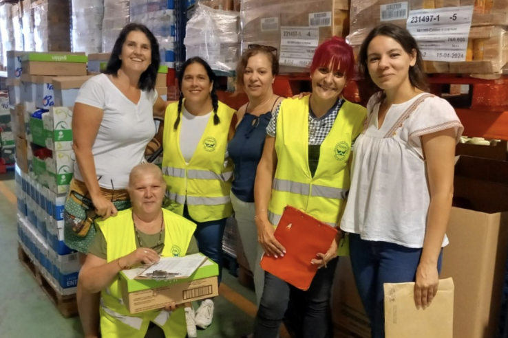 A group of women pose in a warehouse wearing neon vests