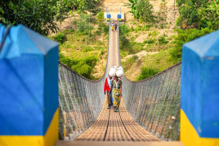 Two people walking across the the Gahira Bridge in Rwanda