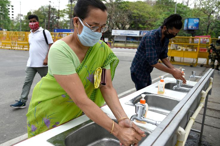 masked woman washing hands and social distanced