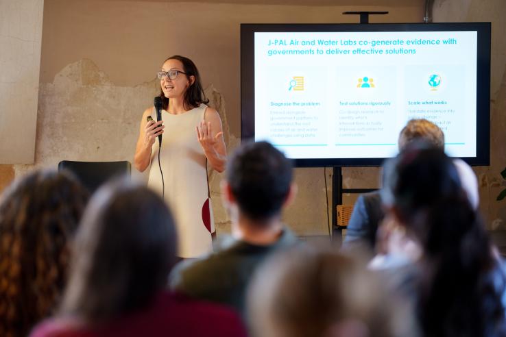 A woman stands in front of a TV with a powerpoint on it giving a lecture
