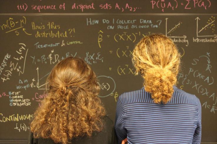 Two women looking at blackboard