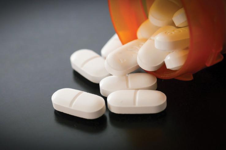 White pill capsules spilling from prescription bottle