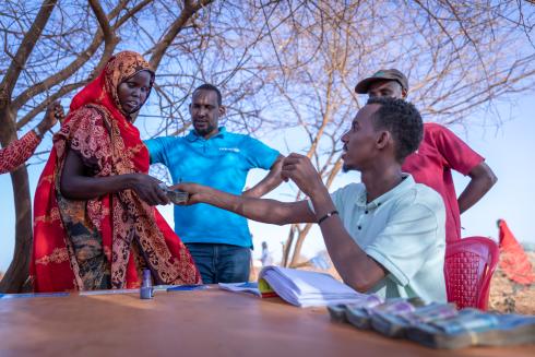 Man sitting handing cash to a woman