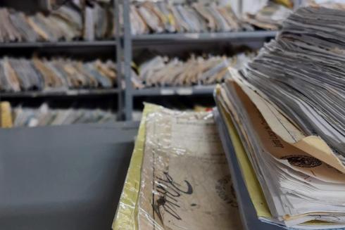 Stack of files in focus with several more on shelves in the background